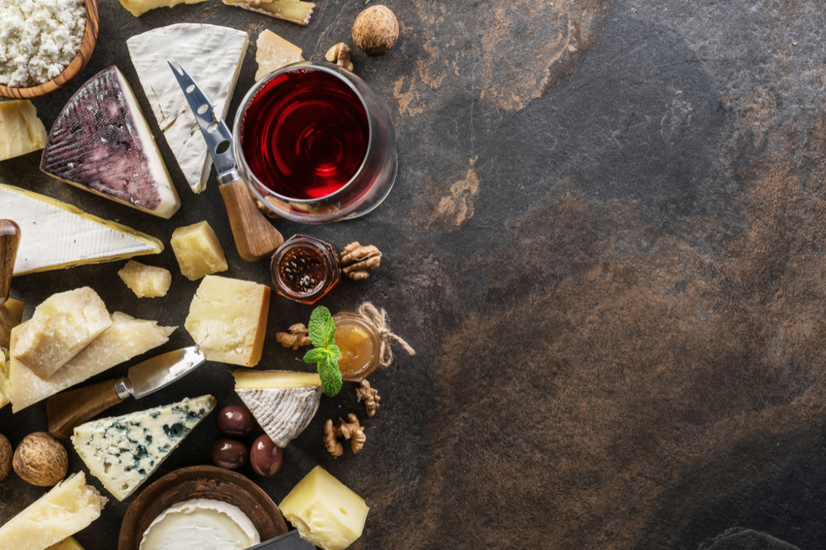 Gourmetkombination af vin, ost og chokolade på et rustikt bord